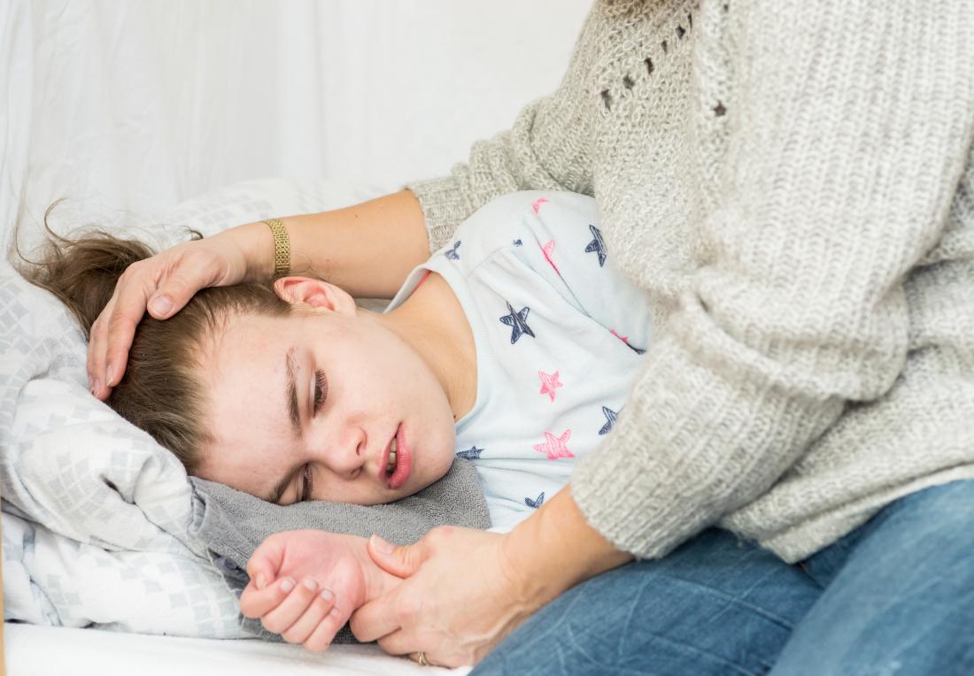 Child on bed with epileptic seizures and convulsions placed in the recovery position.