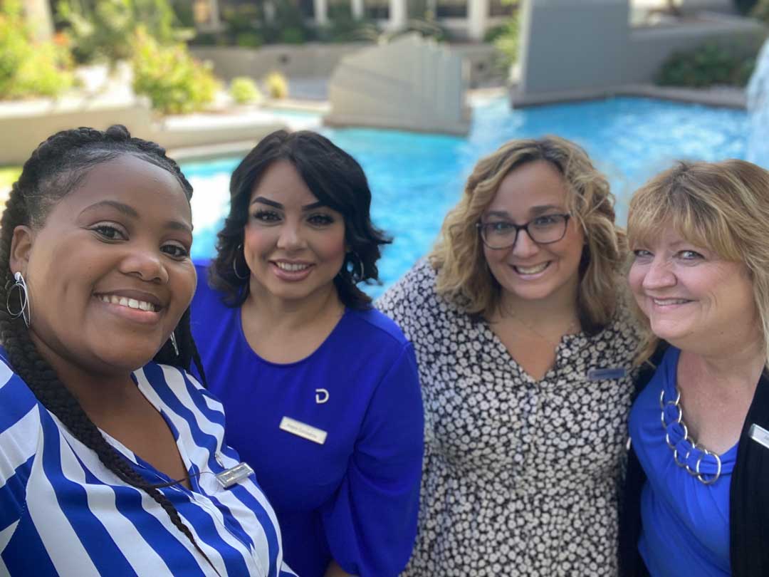 Delta Hotels staff smiling in front of pool