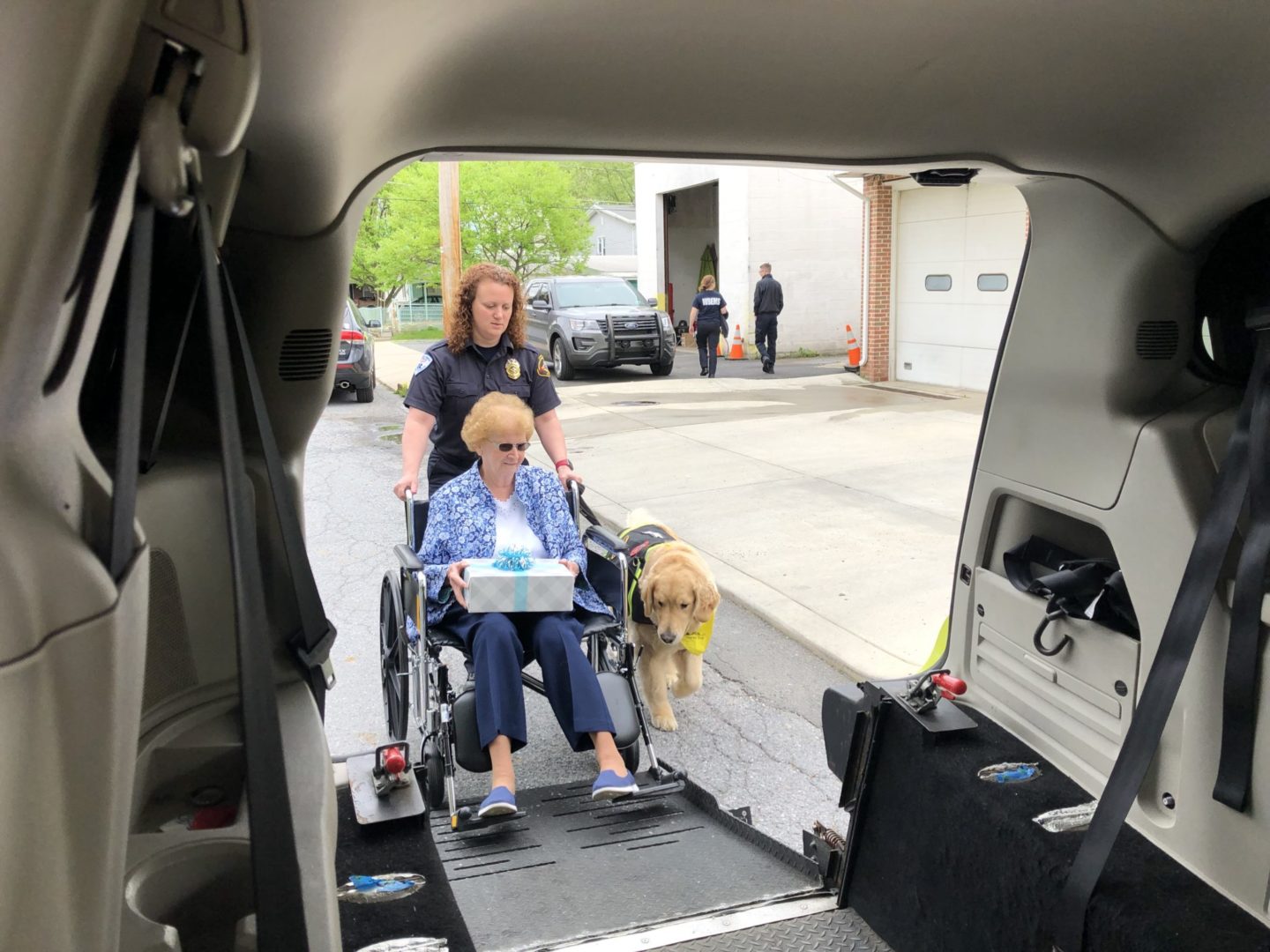 Western Berks staff member helping elderly woman and service dog in ambulance