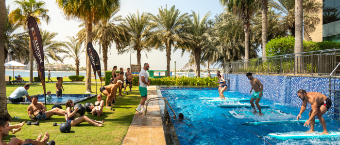 People doing Gym workouts by the pool at Rixos the Palm Dubai. Some are standing on wave surfing boards and some are doing aerobics