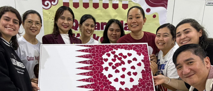 Family Hope Center (3) Family Hope Center staff Celebrating Qatar National Day posing with the Qatar national flag made of flowers