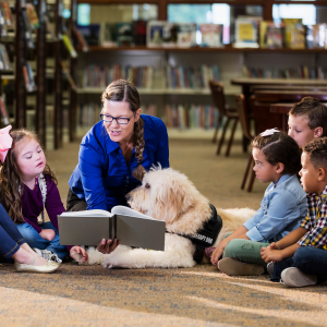 Librarian with service dog reading to a group of children.