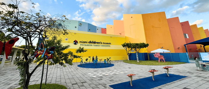Exterior view of the colorful Miami Children's Museum with playful outdoor sculptures and a blue sky with scattered clouds.