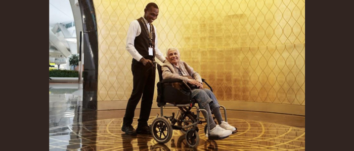 POD person on a wheel chair getting help by Zayed International Airport Staff Member