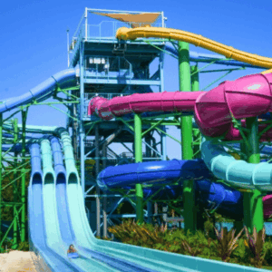 Colorful water park with intertwined blue, pink, green, and yellow slides beneath a bright blue sky.
