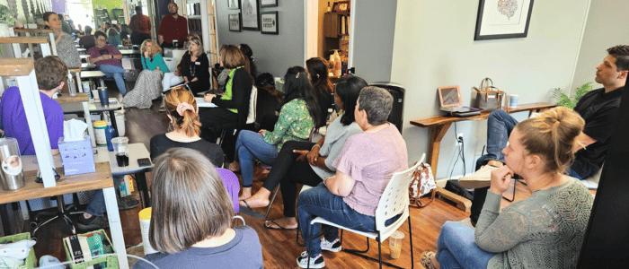 LearningRx Chattanooga (1) A group of people attentively listening to a speaker in a cozy room filled with chairs, shelves, and natural light.